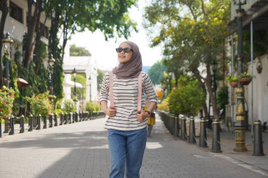 Siyah güneş gözlüğü takan Asyalı Müslüman kadın Kota Lama ya da Old Town CIty, Semarang, Endonezya 'da sokakta yürüyor.