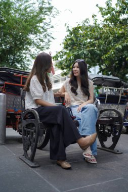 Sokağın kenarında oturan iki Asyalı kadın.
