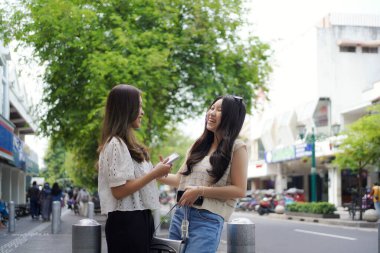 Malioboro Caddesi, Yogyakarta, Endonezya 'da konuşurken ve gülümserken iki Asyalı kadın.