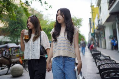 Mutlu Asyalı iki kadın içki içerken Malioboro caddesinde yürüyorlar, Yogyakarta, Endonezya