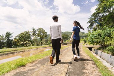 Kırsal bölgede etkin Asyalı çiftlerin yürüyüş egzersizlerinin arka görüntüsü