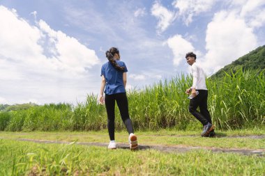 Kırsal bölgede etkin Asyalı çiftlerin yürüyüş egzersizlerinin arka görüntüsü