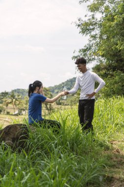 Aktif Asyalı genç çift kırsal bölgedeki egzersiz ve su şişesinden su içmeye ara verir.