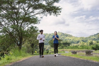 aktif Asyalı genç çift kırsal alanda koşuyor ve koşuyor