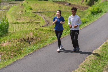 aktif Asyalı genç çift kırsal alanda koşuyor ve koşuyor