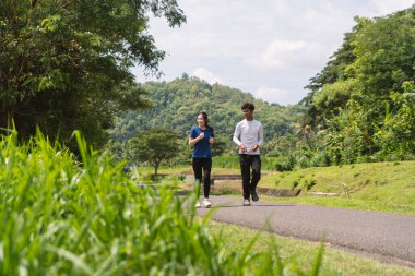 aktif Asyalı genç çift kırsal alanda koşuyor ve koşuyor