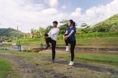 Aktif genç Asyalı çift kırsal alanda egzersiz yapmadan önce geriniyor.