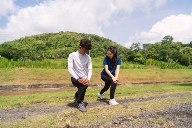 Aktif genç Asyalı çift kırsal alanda egzersiz yapmadan önce geriniyor.