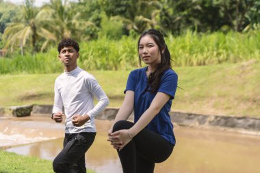 Aktif genç Asyalı çift kırsal alanda egzersiz yapmadan önce geriniyor.