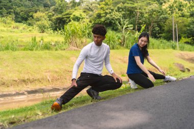 Aktif genç Asyalı çift kırsal alanda egzersiz yapmadan önce geriniyor.