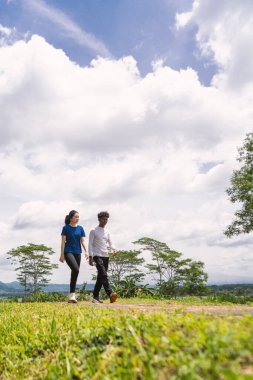 Kırsal bölgede yürürken su şişesi tutan aktif genç Asyalı çift.
