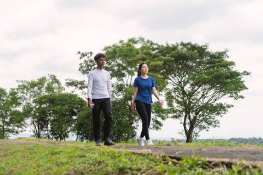 Kırsal bölgede yürürken su şişesi tutan aktif genç Asyalı çift.