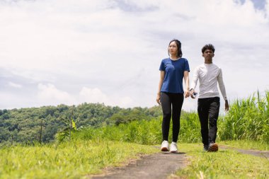 Kırsal bölgede yürürken su şişesi tutan aktif genç Asyalı çift.