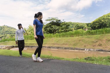 aktif genç Asyalı çift kırsal alanda yürüyüş egzersizi yapıyor.