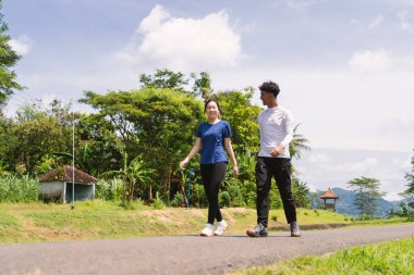 aktif genç Asyalı çift kırsal alanda yürüyüş egzersizi yapıyor.