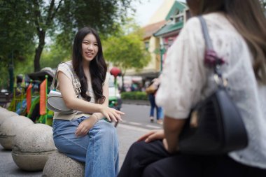 Sokağın kenarında oturan iki Asyalı kadın.