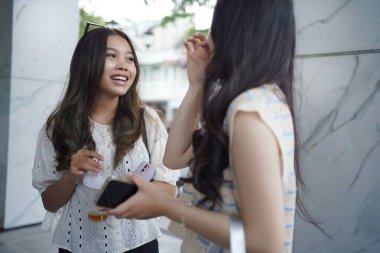 Malioboro caddesinde dikilirken konuşan ve gülümseyen iki Asyalı kadın, Yogyakarta, Endonesi