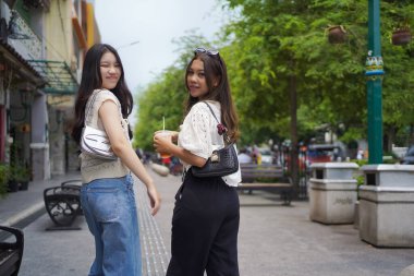 İki Asyalı kadının arka görüntüsü ve Malioboro Caddesi, Yogyakarta, Endonezya 'da yürürken kameraya bakın.
