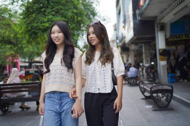 Mutlu iki Asyalı kadın Malioboro caddesinde yürüyor, Yogyakarta, Endonezya