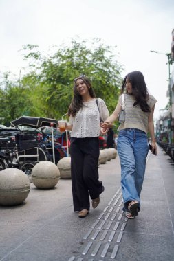 Mutlu iki Asyalı kadın Malioboro caddesinde yürüyor, Yogyakarta, Endonezya