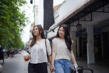 Mutlu iki Asyalı kadın Malioboro caddesinde yürüyor, Yogyakarta, Endonezya