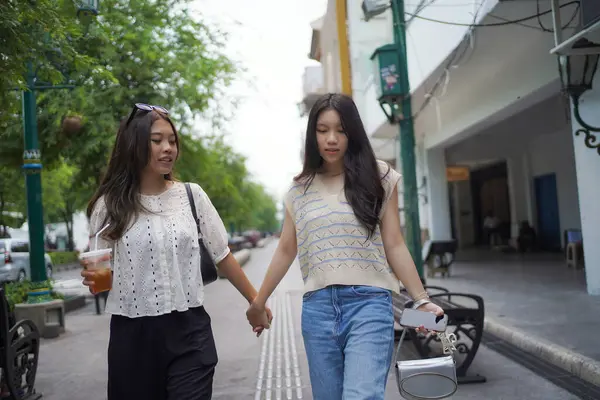 Mutlu iki Asyalı kadın Malioboro caddesinde yürüyor, Yogyakarta, Endonezya