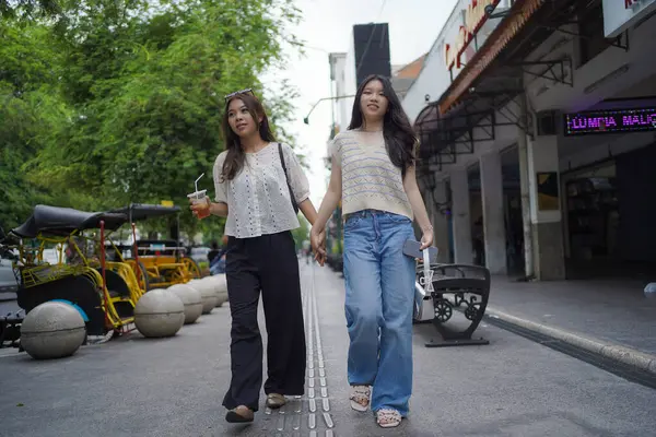 Mutlu iki Asyalı kadın Malioboro caddesinde yürüyor, Yogyakarta, Endonezya