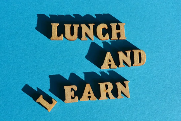 Lunch and Learn, Earn, words in wooden alphabet letters isolated on bright blue background