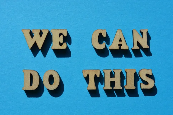 We Can Do This, words in wooden alphabet letters isolated on blue background