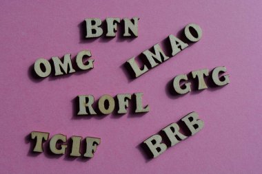 BRB, Be Right Back ve BFN gibi kısaltmalar, pembe arka planda izole edilmiş ahşap alfabe harfleriyle şimdilik hoşça kalın.