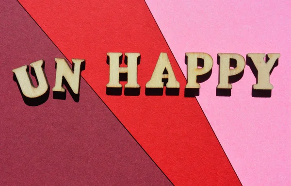 Happy, Unhappy, word in wooden alphabet letters isolated on colourful background