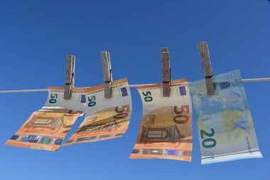 Creative Concept, money laundering. Euro banknotes pegged on a washing line to dry, blowing in the wind clipart