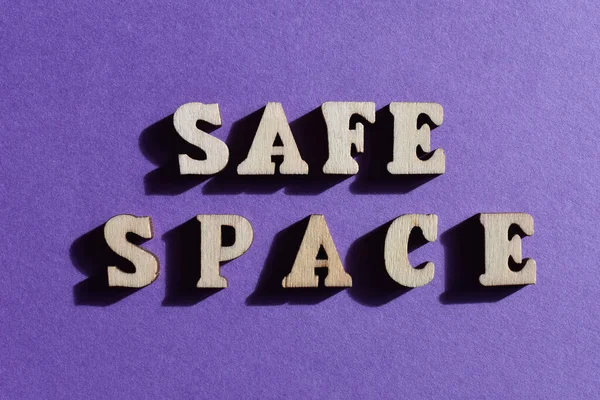 Safe Space, words in wooden alphabet letters isolated on purple background