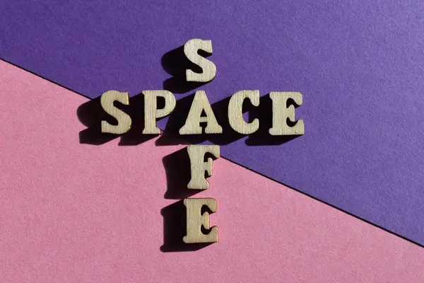 Safe Space, words in crossword form in wooden alphabet letters isolated on pink and purple background