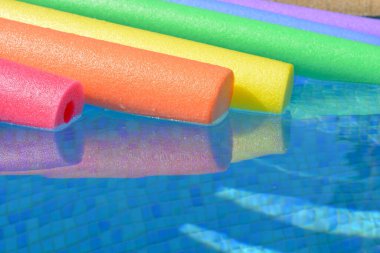 Suyun üzerinde yüzen parlak ve renkli havuz erişteleri.