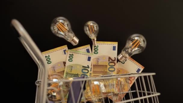 Strompreis Europa Glühbirnen Und Eurogeld Nahaufnahme Einem Einkaufswagen Auf Schwarzem — Stockvideo