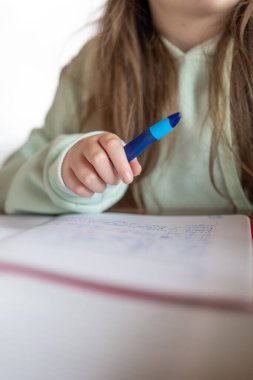 Ödev. Ödev ve eğitim konsepti. Öğrenci kız ödevini yapıyor. Çocuk not defterine kurşun kalemle yazıyor. Çocuktaki kalemi yakın çekim..