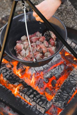 Kazanda et var. Ateşte yemek var. Kazanda et pişirmek. Sokak yemeği. Açık havada ve dışarıda yemek pişirmek. Kamp yapmak..