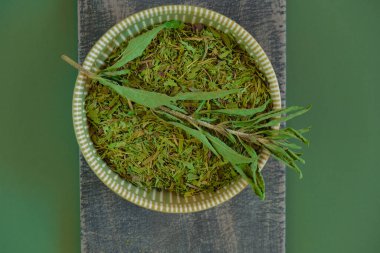 Kurumuş stevia ve yuvarlak bir fincanda yeşil dal, koyu zeytinli arka planda tahta bir tahtanın üzerinde. Şeker yerine. Doğal beslenme tatlandırıcı.