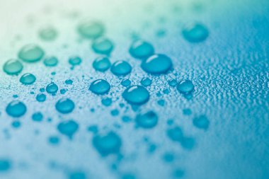 Su mavi bir zemine düşer. Sıvı dokusu soğuk mavi tonlarda. Duvar kağıdı Blau phone.Makro damlaları ayarlandı.