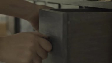 Kayıp bir şeyi ara. Ara, kaybet, kayıp eşya konsepti. Eller bulanık, karanlık bir odada çekmeceleri çekiyor. Yavaş hareket. Dolapları temizliyor. Dolap çekmecesine bakan bir kadın. 4K görüntü.