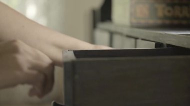 Kayıp bir şeyi arayın. Kayıp bir şeyi arayın. Eller bulanık, karanlık bir odada çekmeceleri çekiyor. Yavaş hareket. Dolap çekmecesine bakan bir kadın. 4k görüntü
