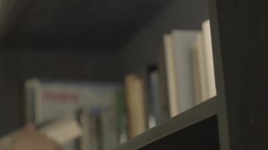 Kitap rafları. Eller kitapları raflara koyar. Yumuşak odaklanma. Yavaş hareket. Kitap okuma kavramı. Edebiyat ve okuma kavramı. 4k görüntü