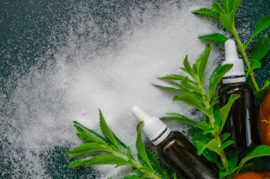 Tatlı yaprak şekeri yerine, diyet, vejetaryen gıda tatlandırıcı.Tatlı bitki, stevia tozu ve sıvı stevia özütü koyu yeşil bir arka planda cam bir şişede bulunur. Doğal şeker yerine.