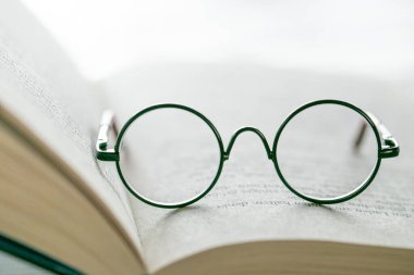 Education and schooling concept.Symbol of study, knowledge and reading.Reading glasses close-up on the pages of a book on a light blurred background.