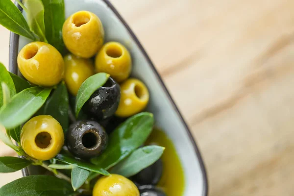 Olives and olive oil.mediterranean cuisine ingredient. Black and green olives and a green olive branch close-up on a wooden table. Fresh bio organic olives and black olives.