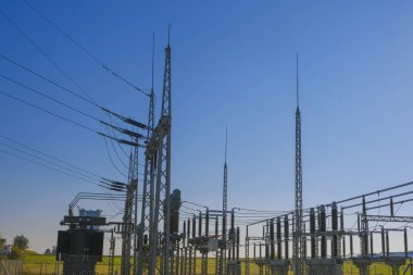  Electricity and energy.Power station in the rays of the sun on a blue sky background.Energy equipment.High tension power. electricity line. Power lines on blue sky background.