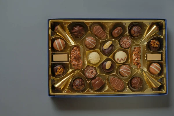 Assorted chocolate candies in a box on a gray background. Chocolate box. Milk chocolate candy.Sweets and desserts.Sweets box in assortment