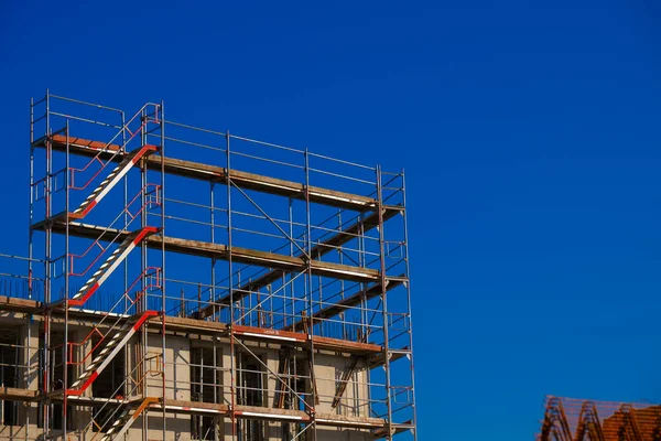 Construction of real estate and industrial premises. house in scaffolding on blue sky background.Building materials and the process of building