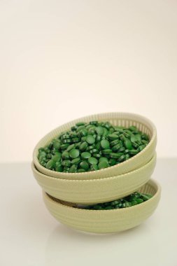 dietary supplements. Spirulina algae tablets.Super food. Spirulina pills in a round green cups set on a light background with reflection.Food supplements for a healthy lifestyle